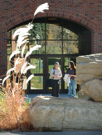 two students talk as they stand in front of the College of Education building