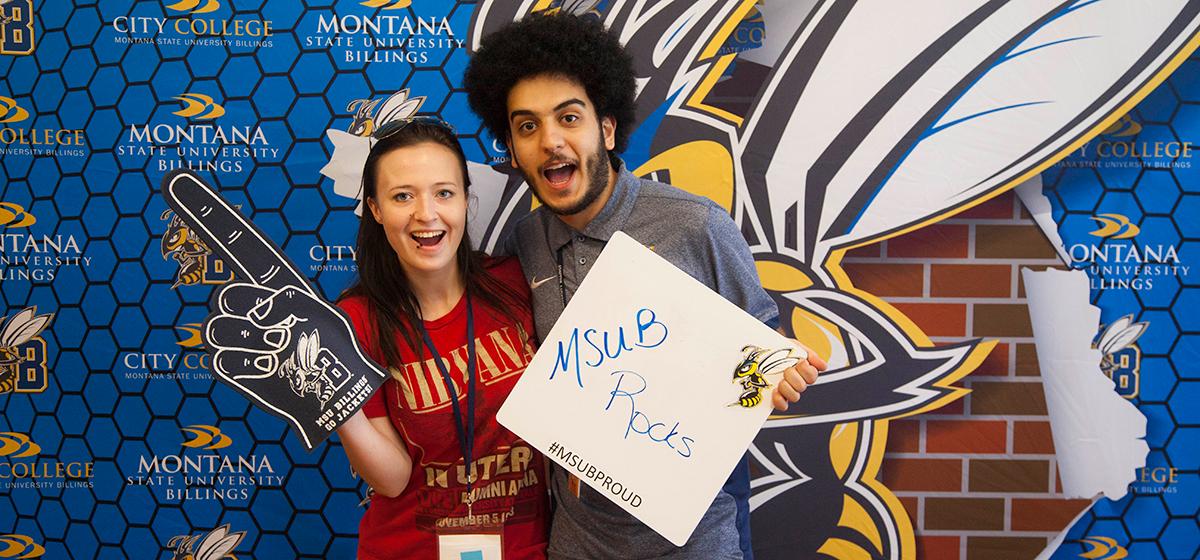 Two students pose in front of MSUB backdrop.