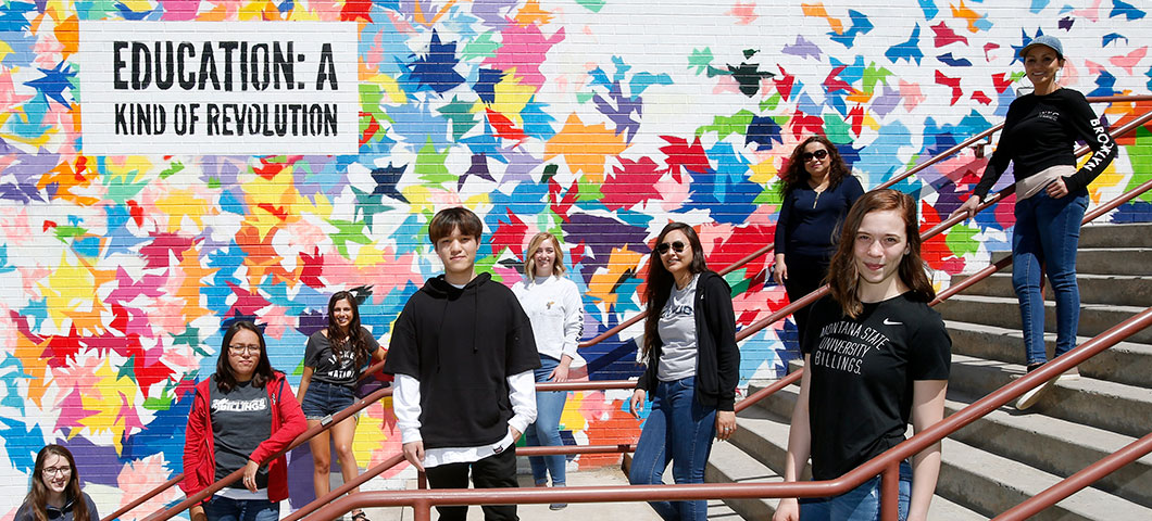 Students in front of a mural reading "Education: A Kind of Revolution"