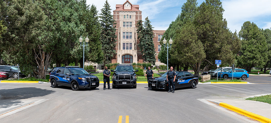 Campus police officers with their cars in front of McMullen.