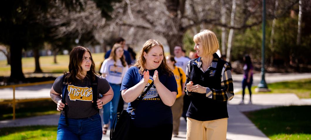 Chancellor Hicswa walking across campus with two MSUB students