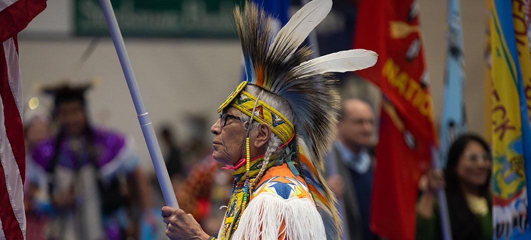 An elderly man wearing traditional Native American garb.