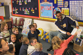 Yellowjacket men's basketball player reading to grade school children.