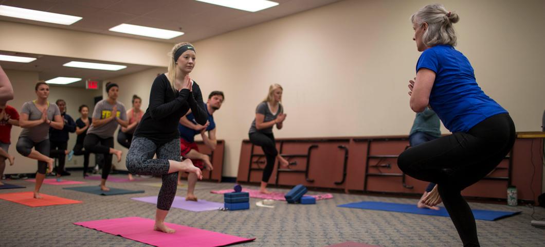 a yoga class holding the standing pigeon pose