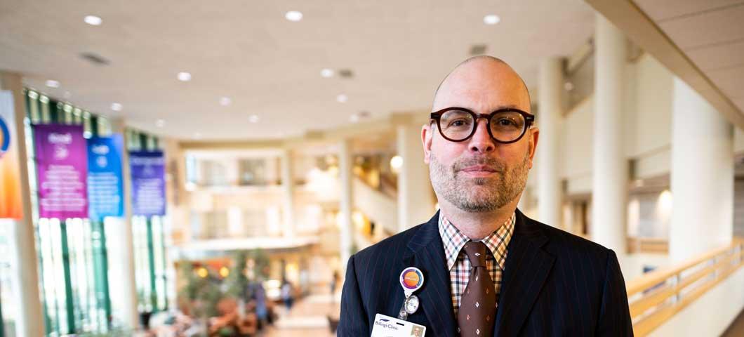 man in suit coat and tie stands in hospital interior balcony