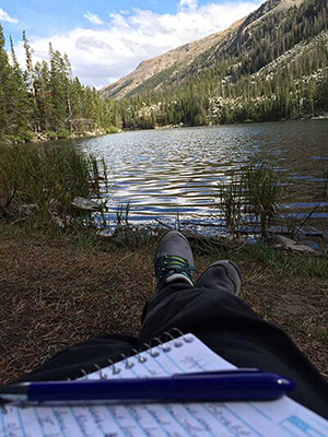 A camper enjoying mountain scenery and taking notes