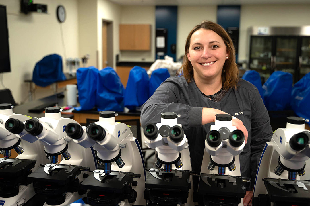 Dr. Madison Collins standing over many microscopes