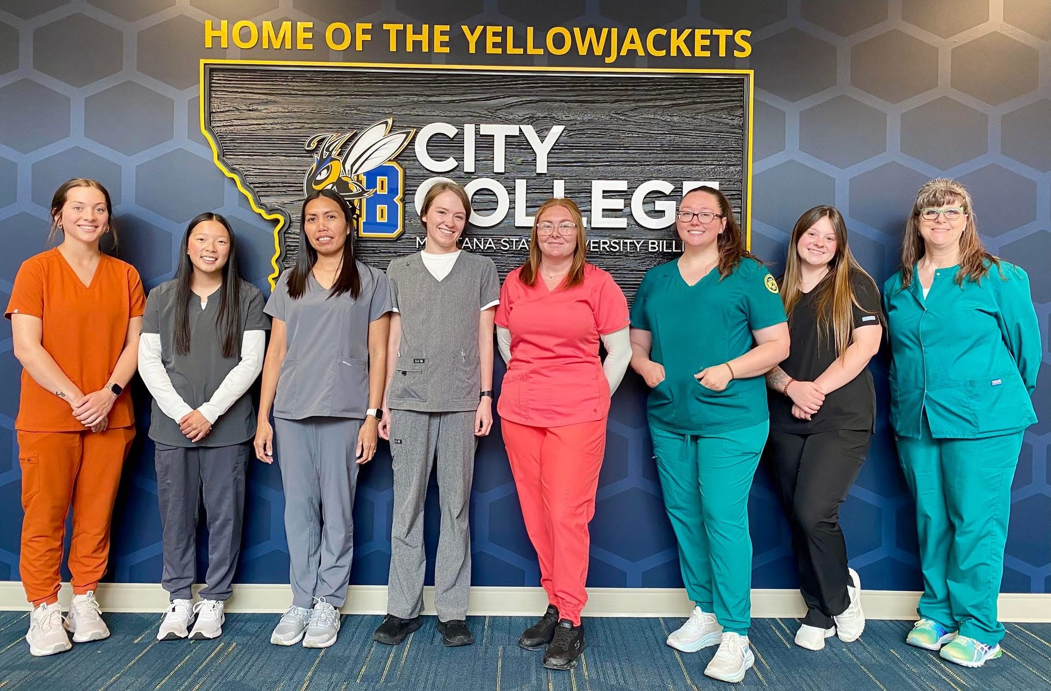 CNA Graduates standing in front on City College logo