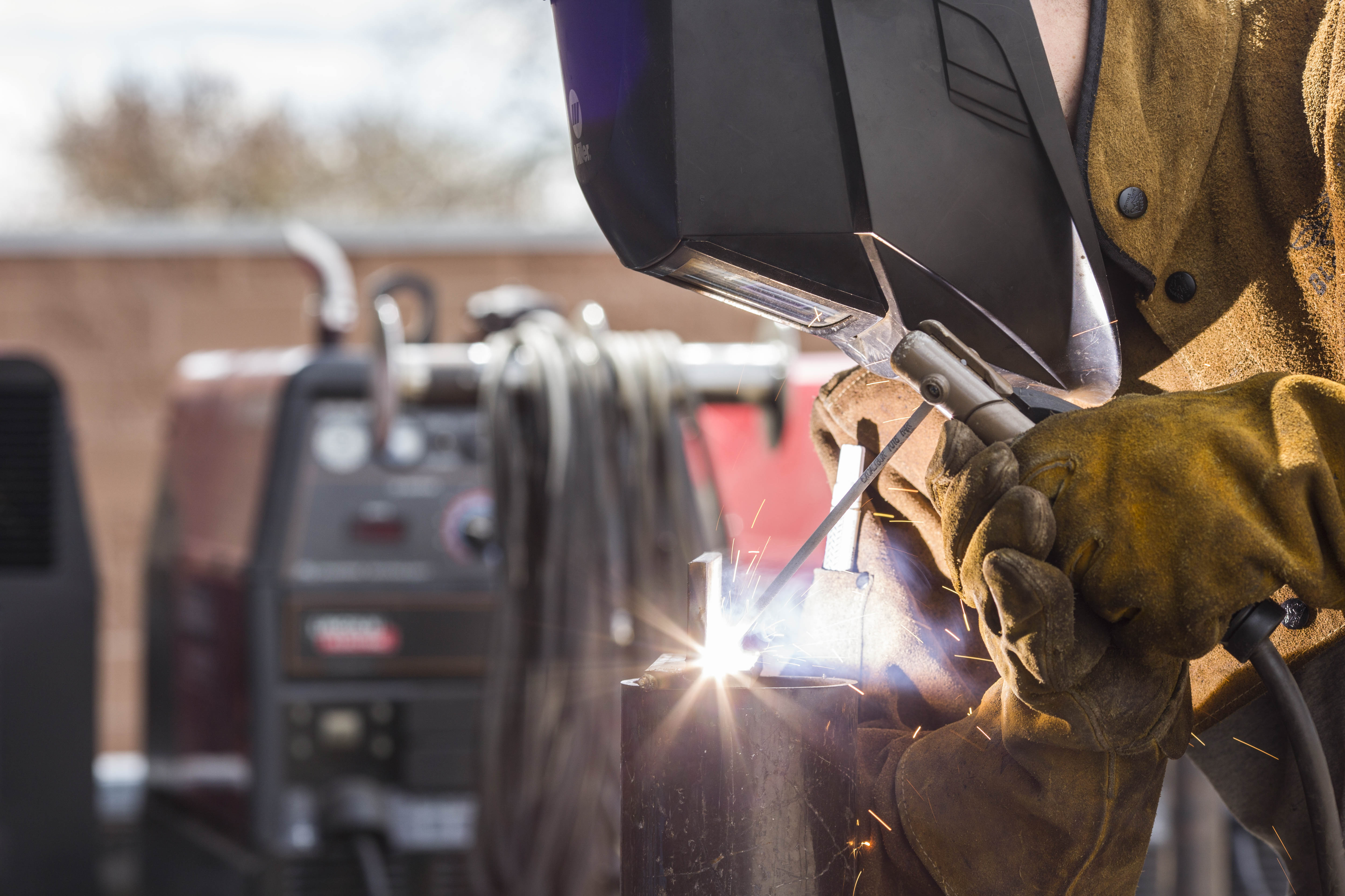Person wearing welding helmet using a welding rod