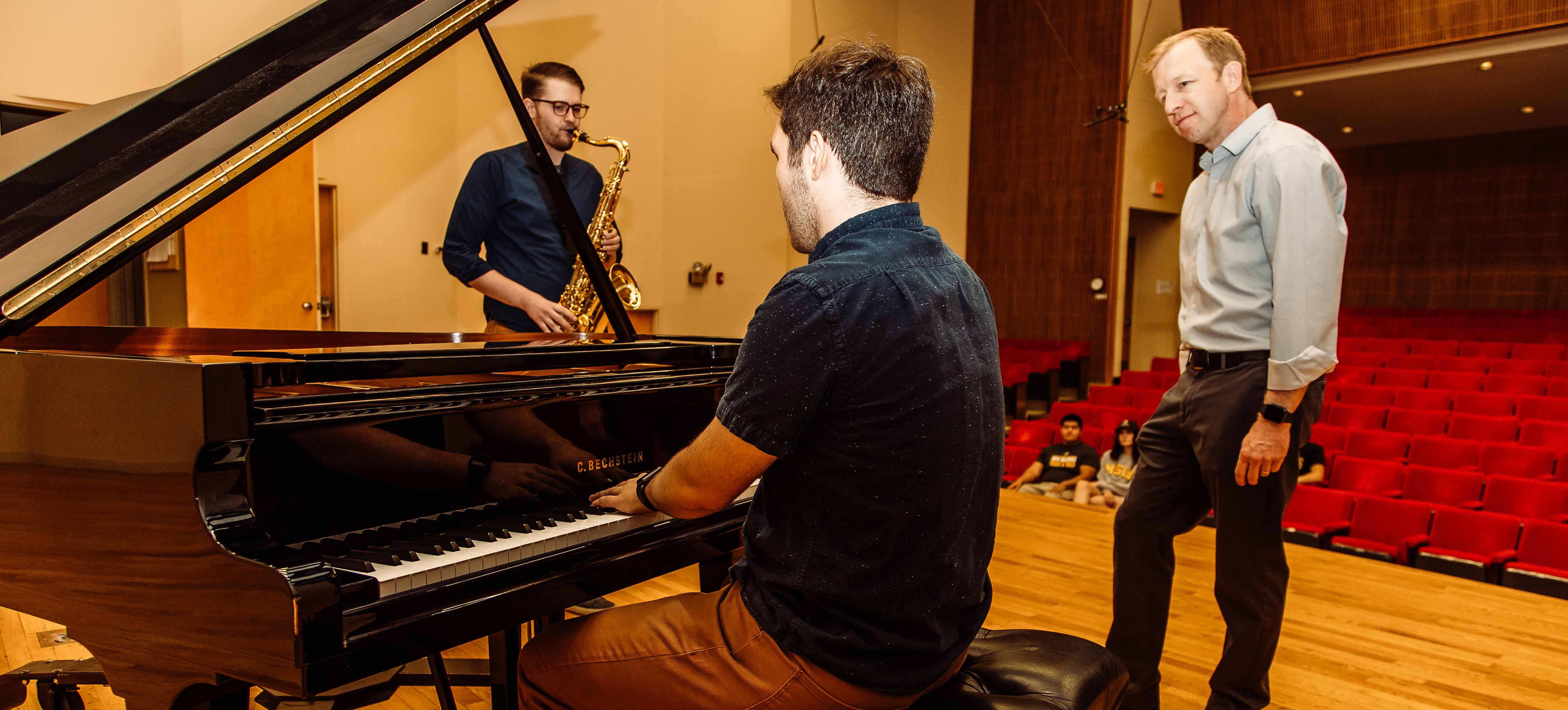 Students playing music instruments and faculty member watching them.