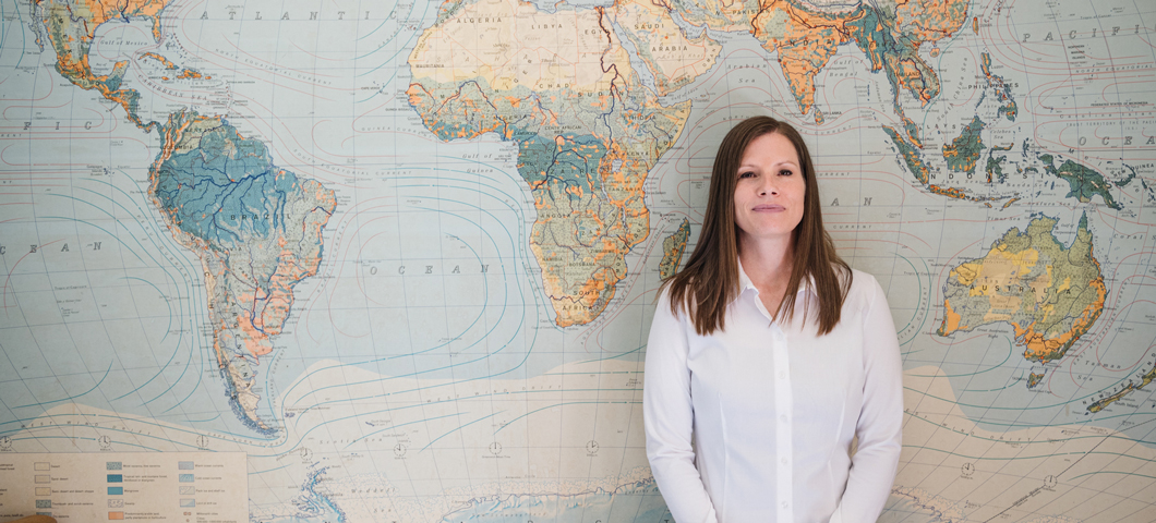 Beth Nelson standing in front of a world map