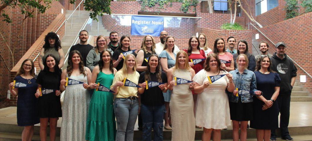 A large group of graduating students holding pennants.