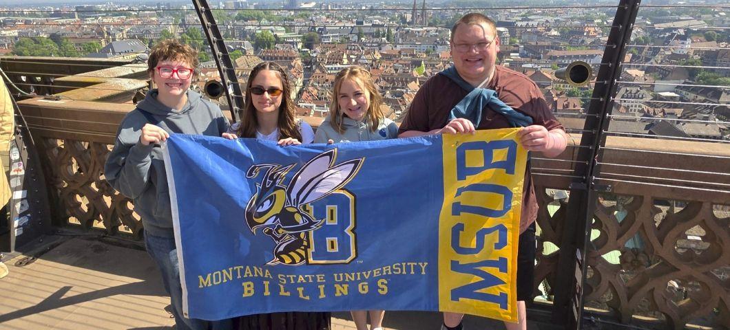Four COE students hold an MSUB flag on a rooftop in Germany