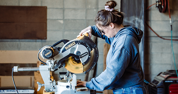young woman operating a chop saw