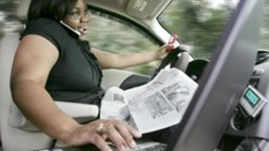 woman driving while typing on laptop and talking on phone