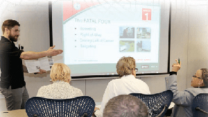 teacher speaking in front of a projection screen