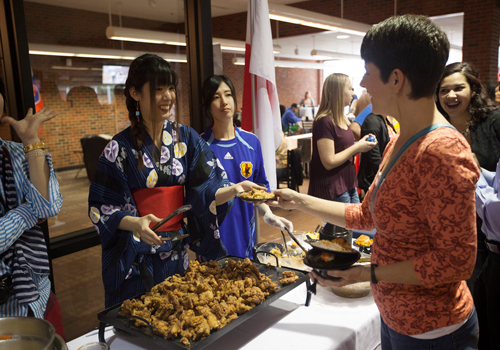 International students at food fair, serving food