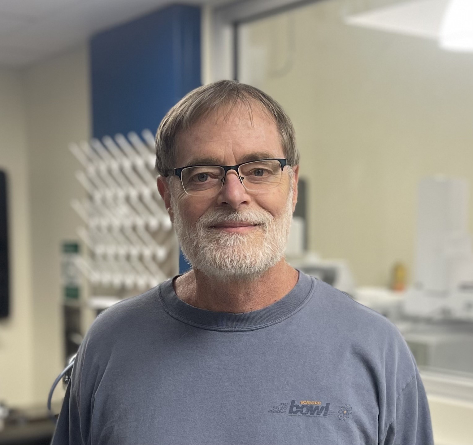 A smiling middle-aged man standing in a science lab