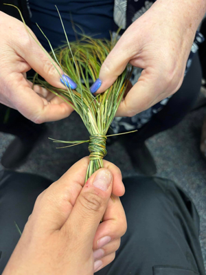 two people braiding sweetgrass