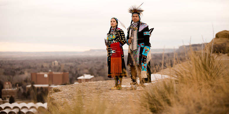 Two students in powwow regalia standing on the Rims