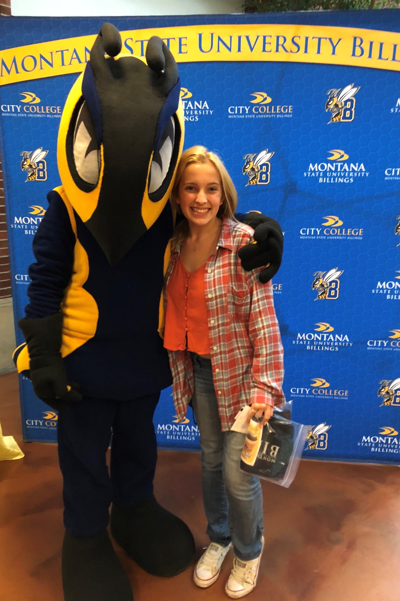 Ashley Clark standing with Buzz (mascot)