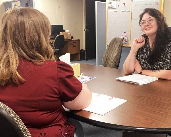 A peer mentor sits at a table having a discussion with a student.