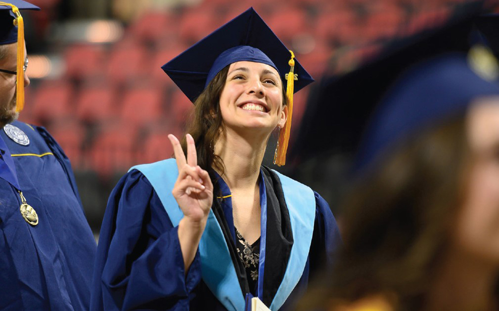 graduating student gives the peace sign to family and friends