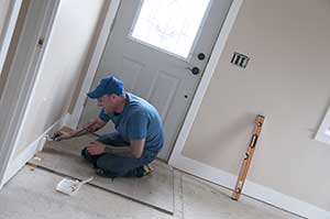 a City College student paints the baseboard in the new modular home