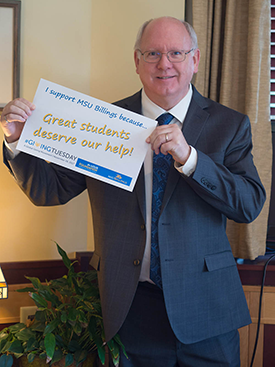 Chancellor Larson with a sign supporting gifts for scholarships