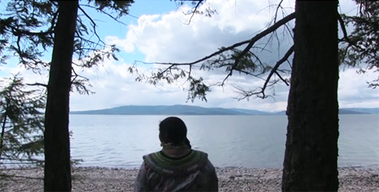 an indigenous woman looking out across a lake
