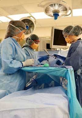 operating room showing surgical technologists and physicians