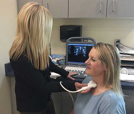 technician performs ultrasound scan of a neck