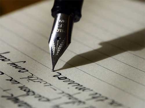 image of a fountain pen writing on lined paper